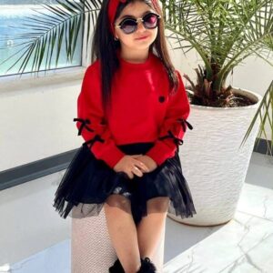 دختر بچه با ست کراپ قرمز آستین پاپیونی و دامن توری مشکی نشسته روی صندلی مناسب شب یلدا.